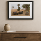 Framed photograph of camels in a desert scene on a wall above a wooden console table.
