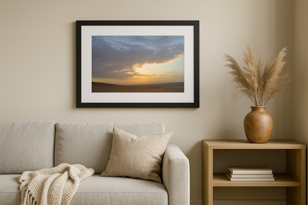 Framed artwork above a sofa with a vase on a side table in a living room setting.
